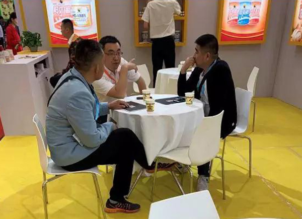 花帝美上美事業(yè)部銷售總監(jiān)張仁杰（中），向客人重點介紹HD速發(fā)蛋糕油、E6024香蕉油香精的適用范圍及使用方法。